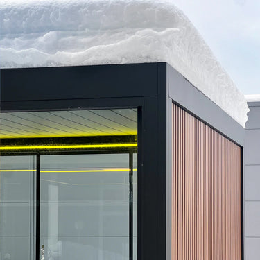 Winterfeste Pergolux Pergola mit Glaswänden, Holzverkleidung und LED-Beleuchtung unter Schneelast.
