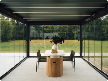 Pergolux Pergola mit Glaswänden, LED-Beleuchtung und modernem Essbereich im Garten.