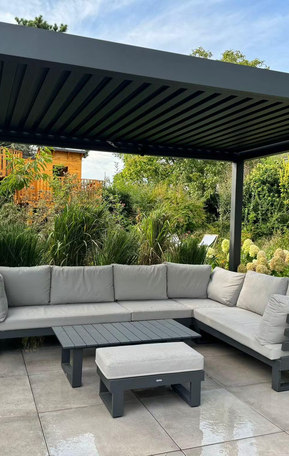 Pergolux Pergola mit Lounge-Möbeln auf Terrasse im grünen Garten.