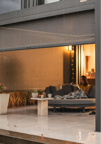 Pergolux Pergola mit geschlossenem Screen und gemütlicher Beleuchtung bei Abendstimmung.