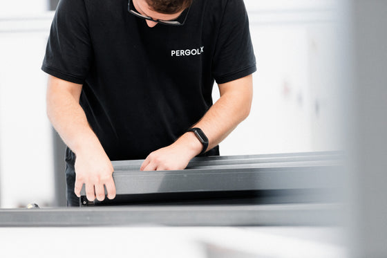 Mitarbeiter mit Pergolux-T-Shirt arbeitet präzise an einem Bauteil in der Produktion.